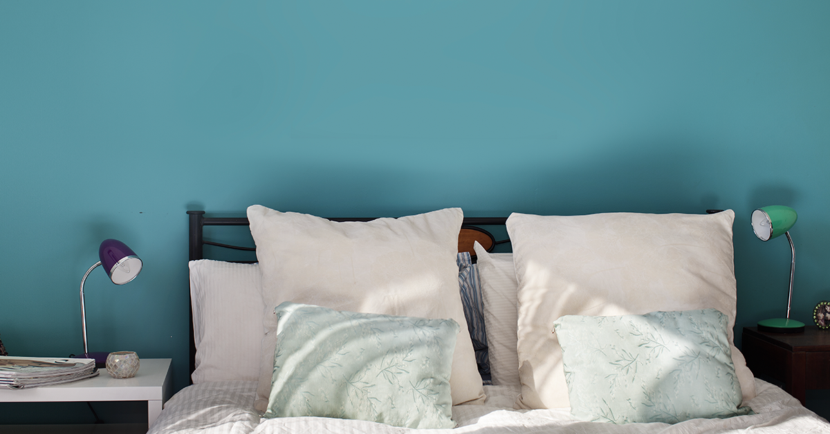 Bed with large with pillows and a blue wall behind