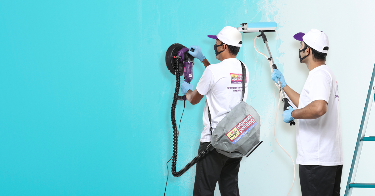 Two men painting a wall light blue