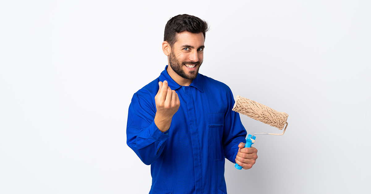 Smiling man in Royal blue shirt with a paint roller in hand