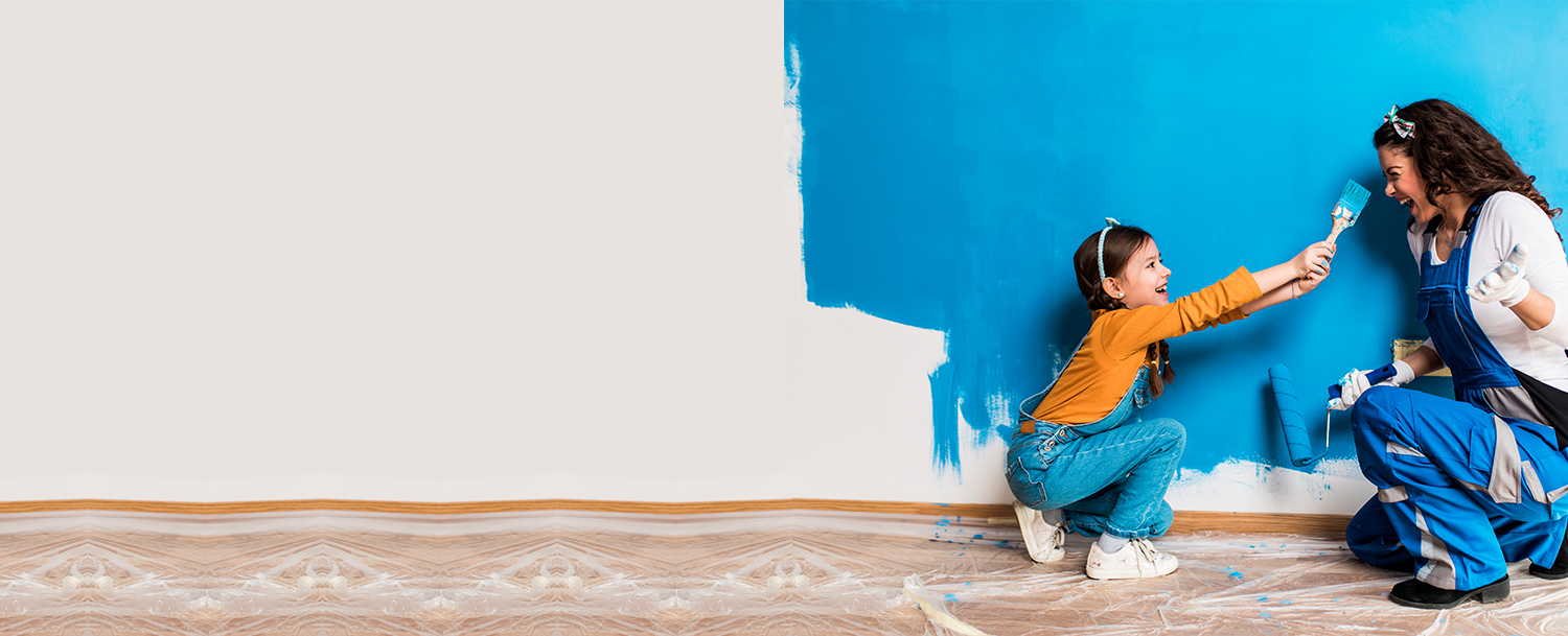 Mother And Daughter Having Fun Painting A Wall Blue